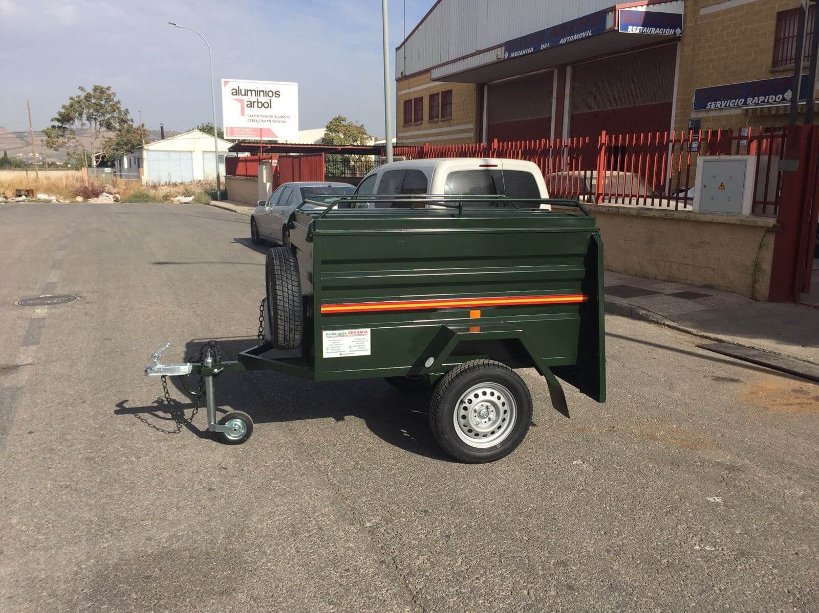 Un remolque verde está estacionado al costado de la carretera frente a un edificio.