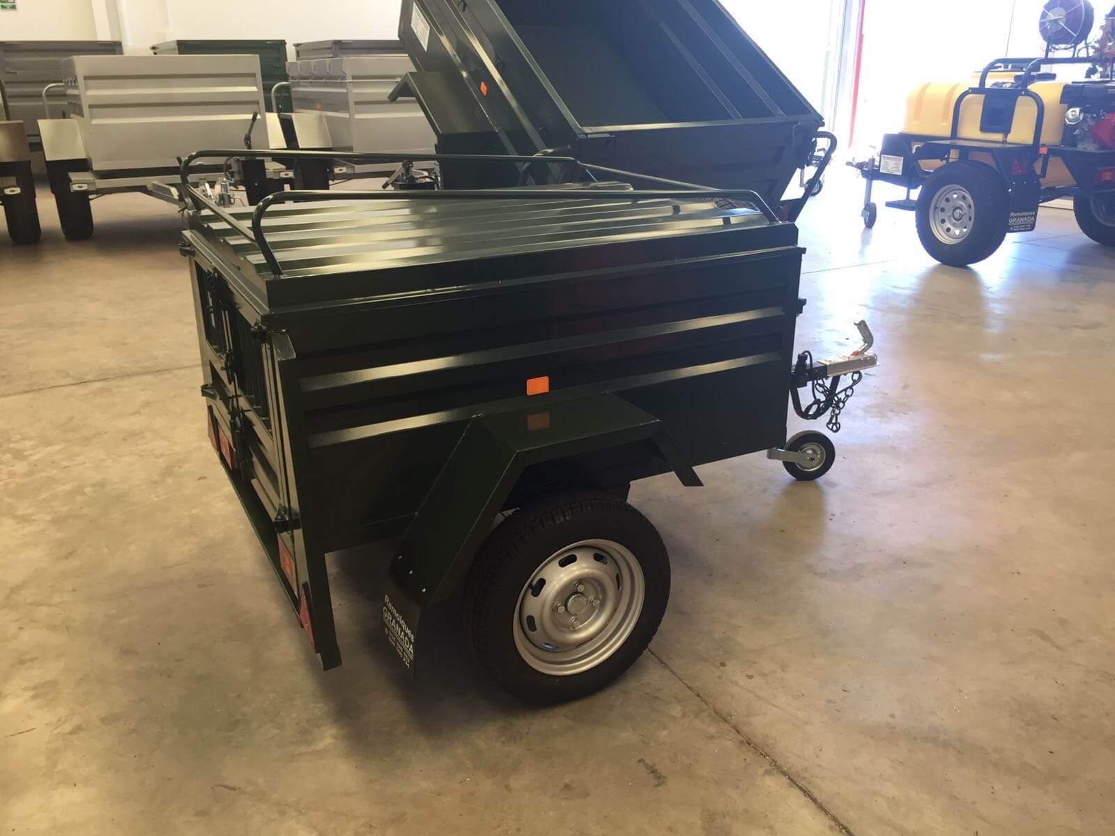 Un remolque verde está estacionado en un garaje al lado de un carrito de golf amarillo.