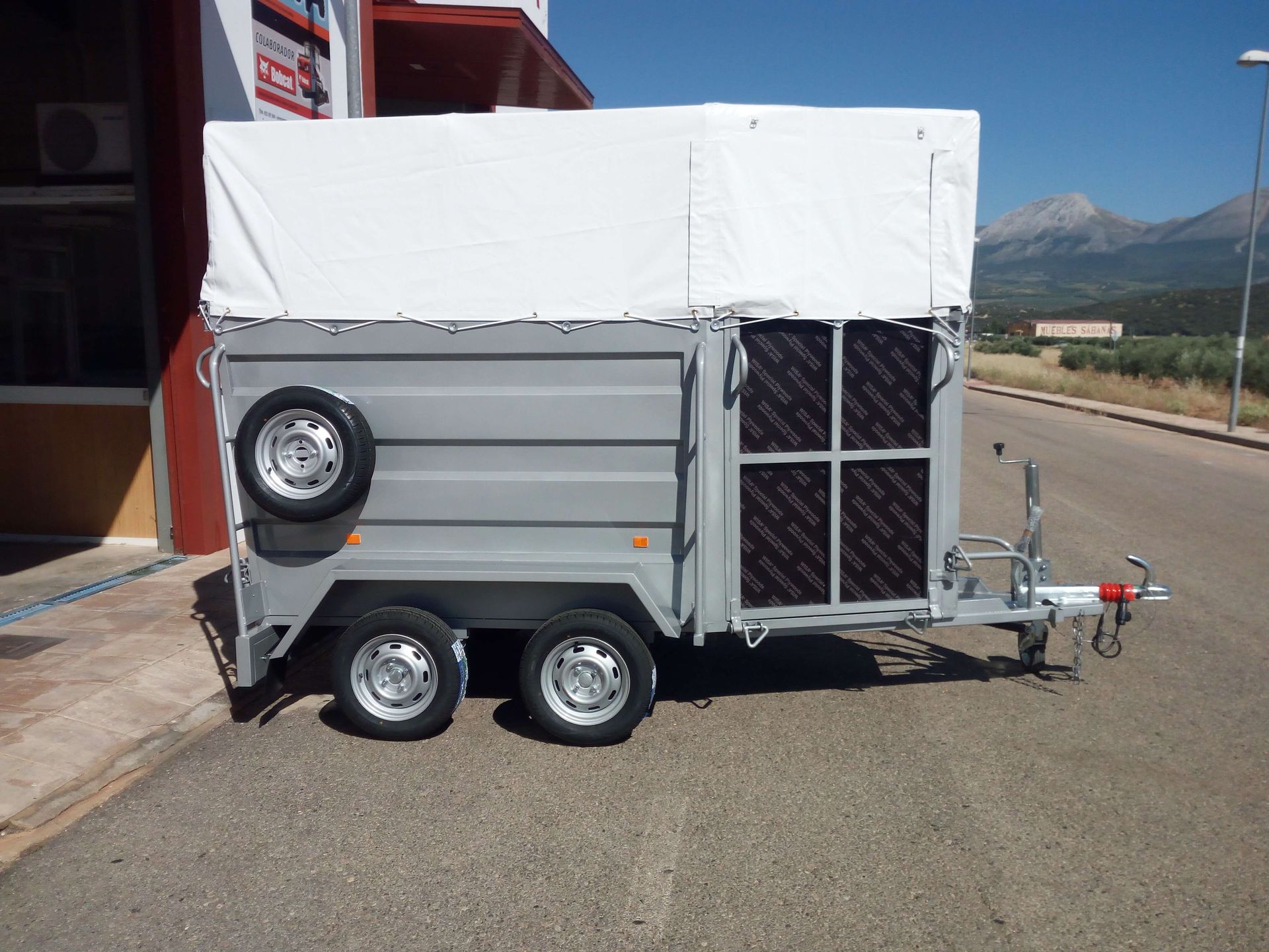 Un remolque con un toldo blanco está estacionado al costado de la carretera.