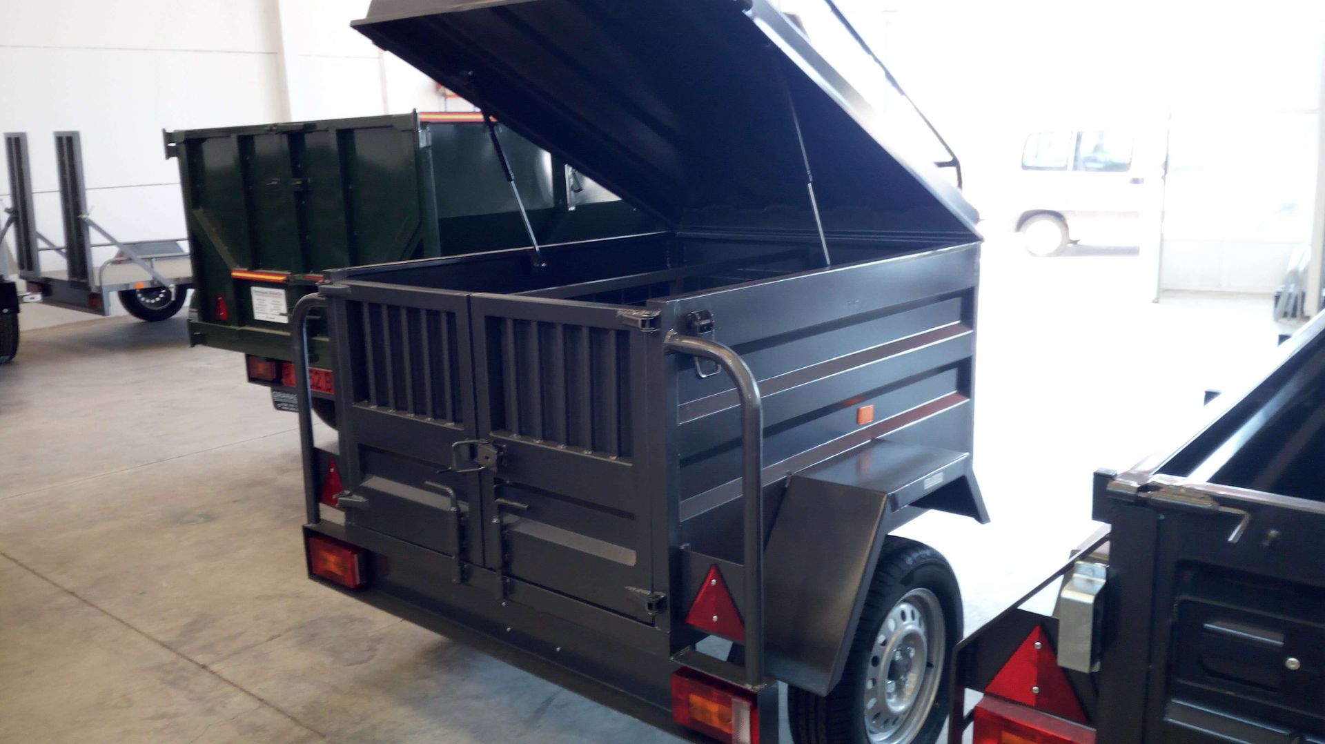 Un remolque negro con la tapa abierta en un almacén.