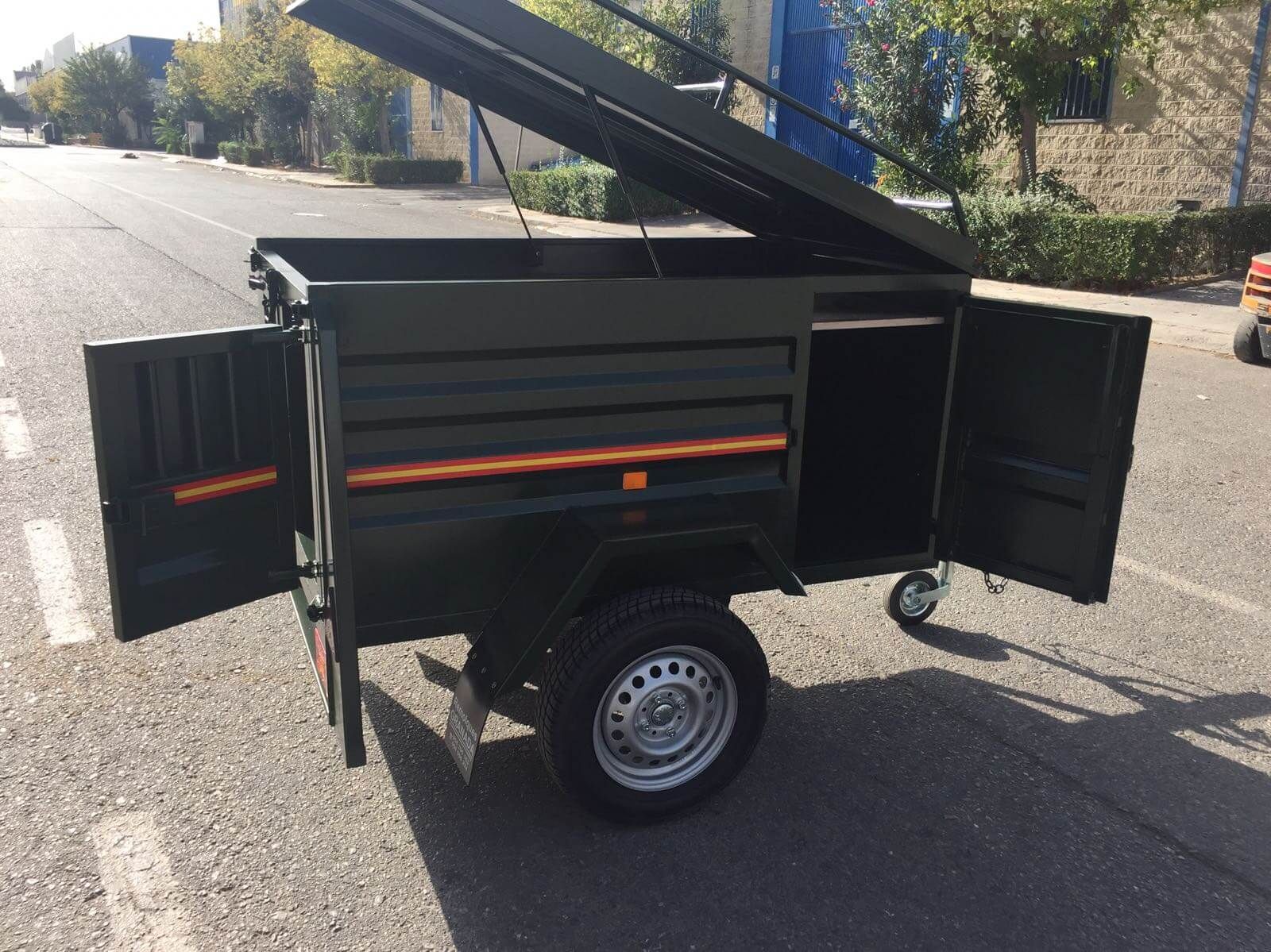 Un pequeño remolque está estacionado al costado de la carretera con las puertas abiertas.