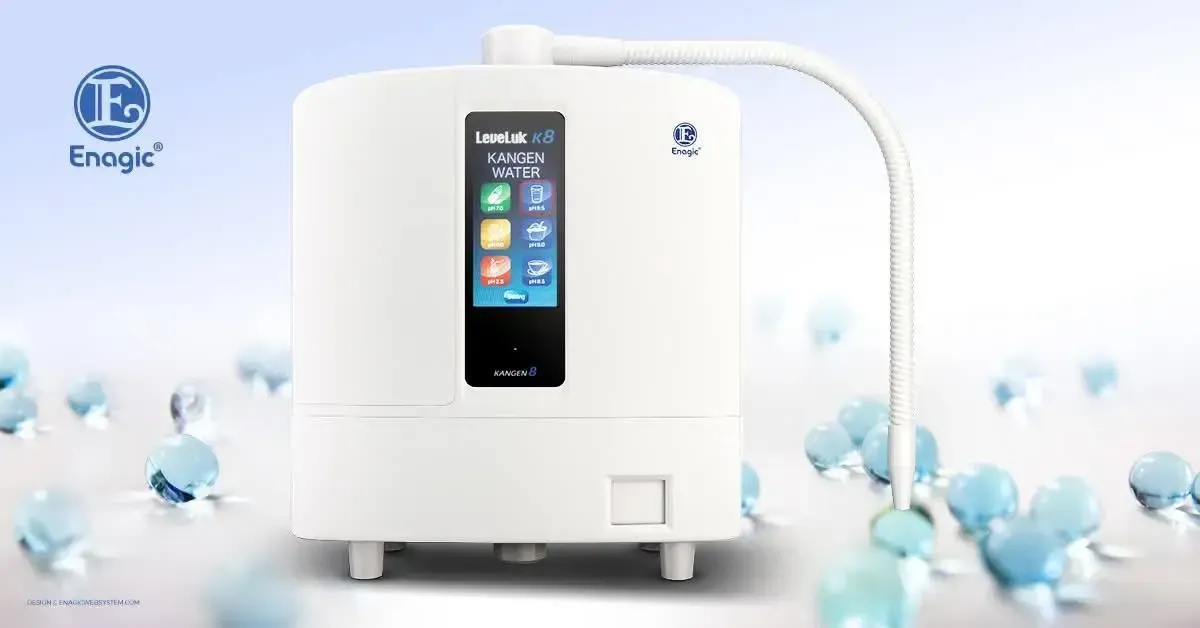 Un vaso de agua clara colocado junto a una jarra de agua a juego sobre una superficie blanca brillante y minimalista.