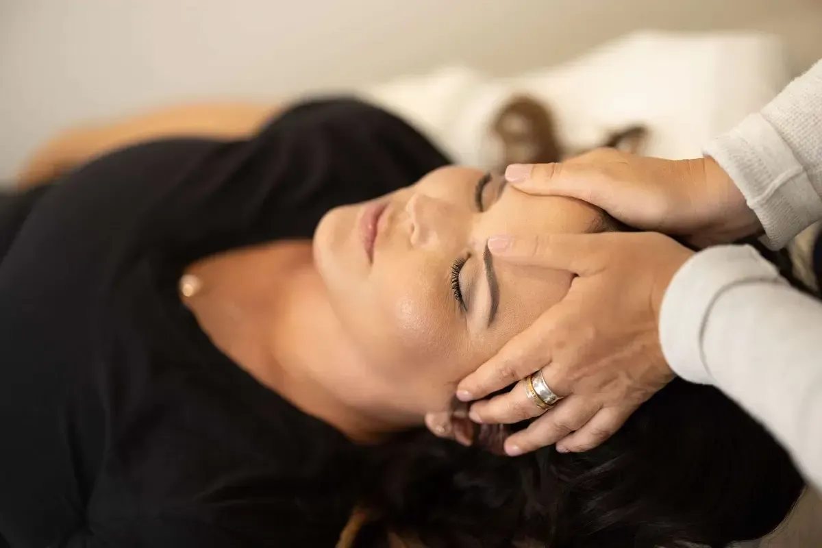 Un grupo de personas tumbadas en el suelo formando un círculo, con los brazos en alto, riendo y mirando hacia arriba