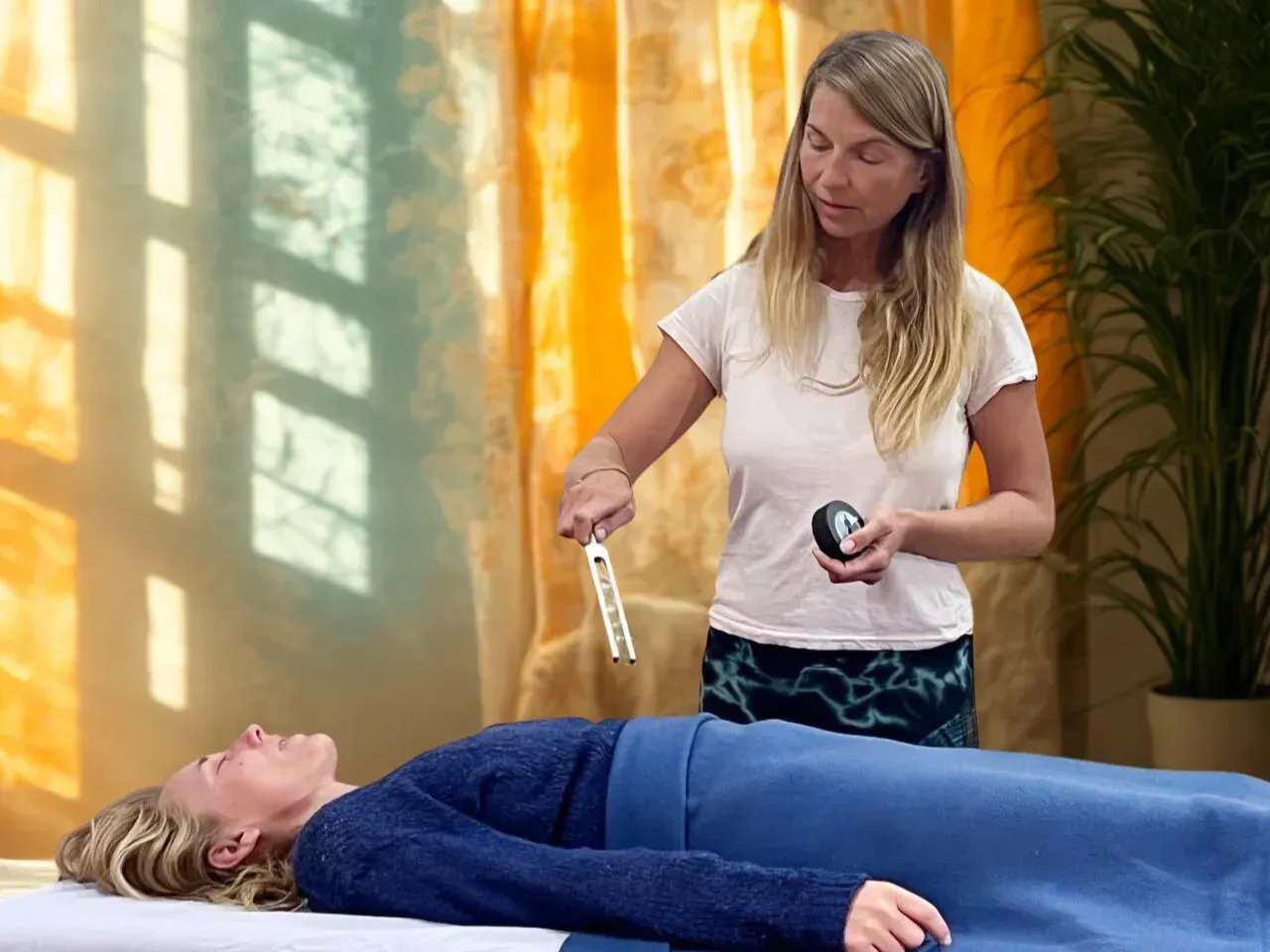 En una habitación luminosa y tranquila, un terapeuta sostiene un diapasón sobre una persona