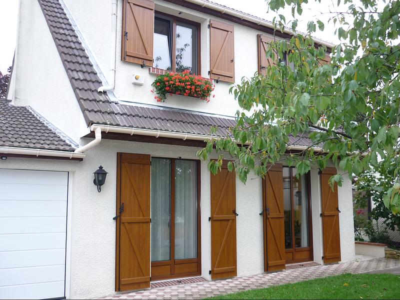 Façade d'une maison avec des volets battants en bois verni