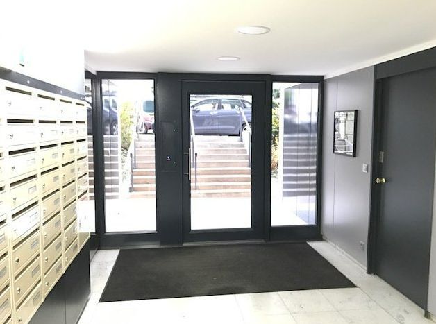 Entrée d'un immeuble avec une porte vitrée et des boîtes aux lettres