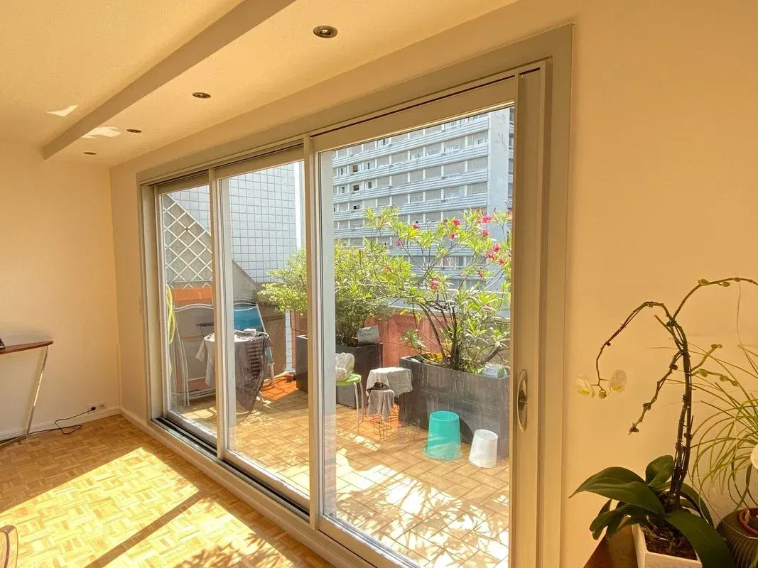 Baie vitrée donnant sur un balcon possédant plusieurs plantes