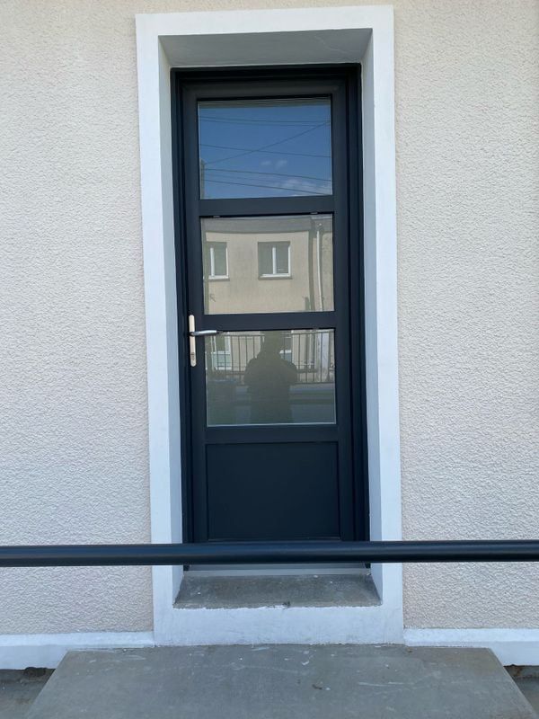 Porte d'entrée noire avec une partie vitrée occultante