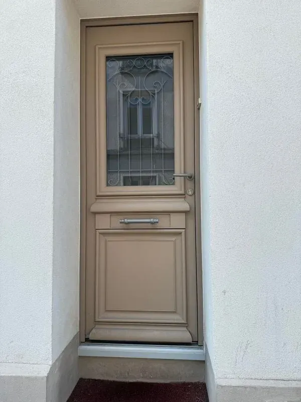 Porte d'entrée vitrée avec des contours en bois clair vu de face