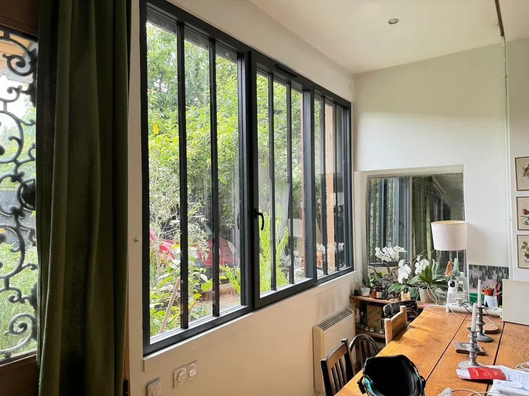 Grande fenêtre aux contours noirs donnant sur le jardin