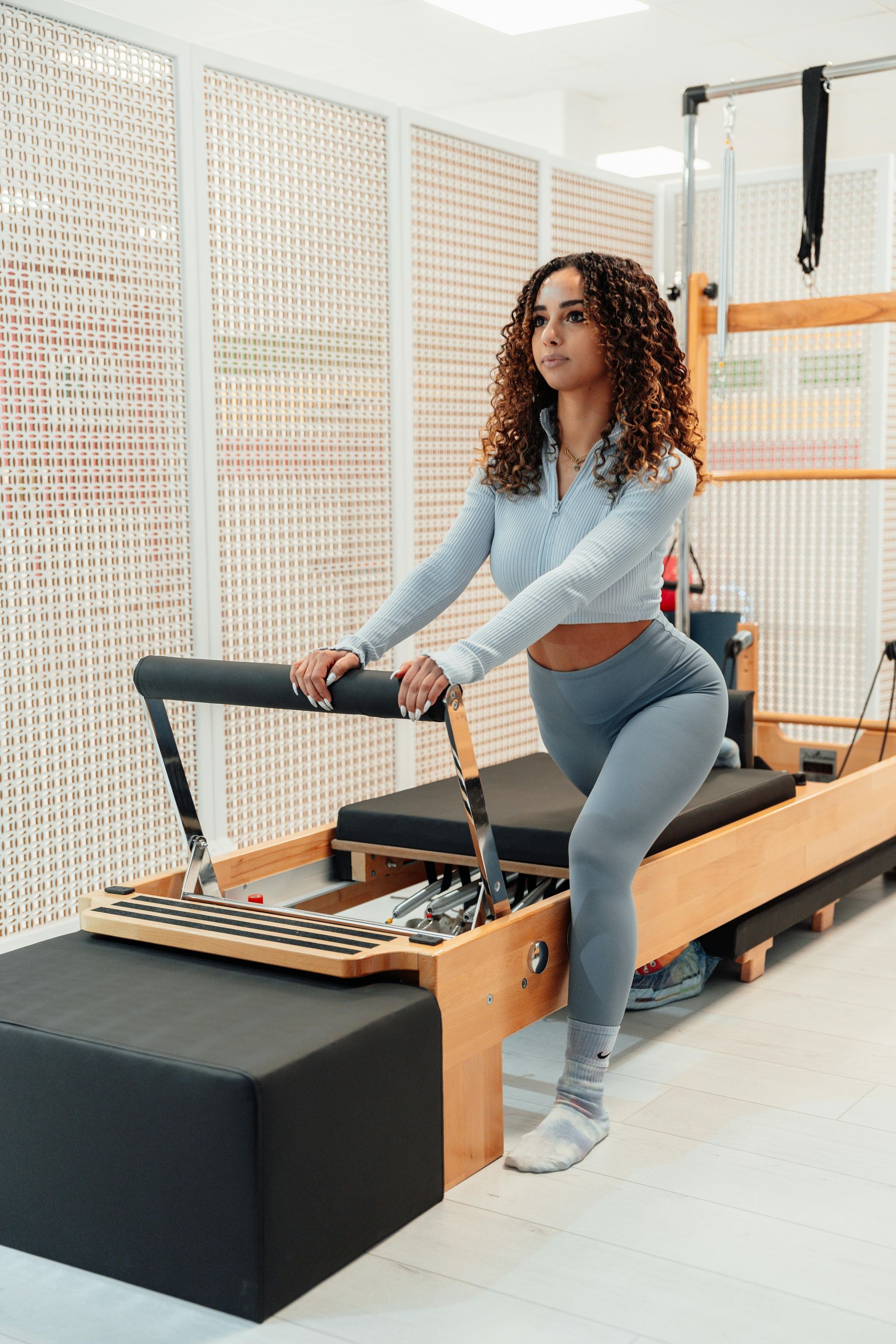 Eine Frau steht in einem Fitnessstudio auf einem Pilates-Gerät.