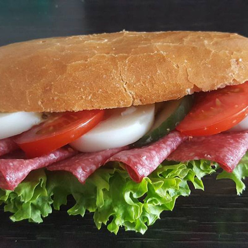 Sub-Sandwich mit Salami, Tomaten, Salat und Eierscheiben auf einem knusprigen Brötchen.