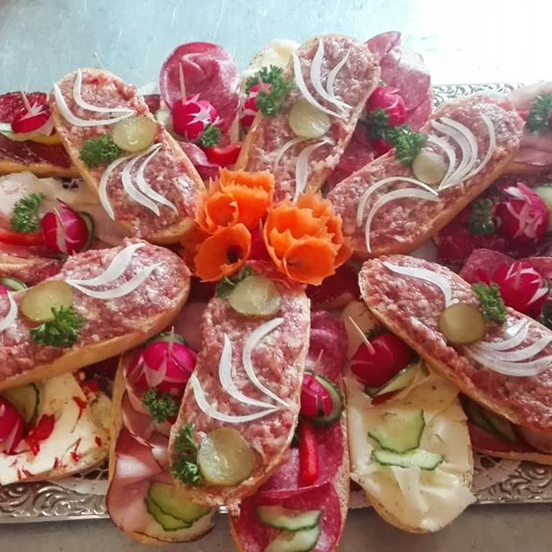 Vorspeisenplatte mit belegten Brötchen mit Fleisch, Zwiebeln, Gurken und Radieschen.