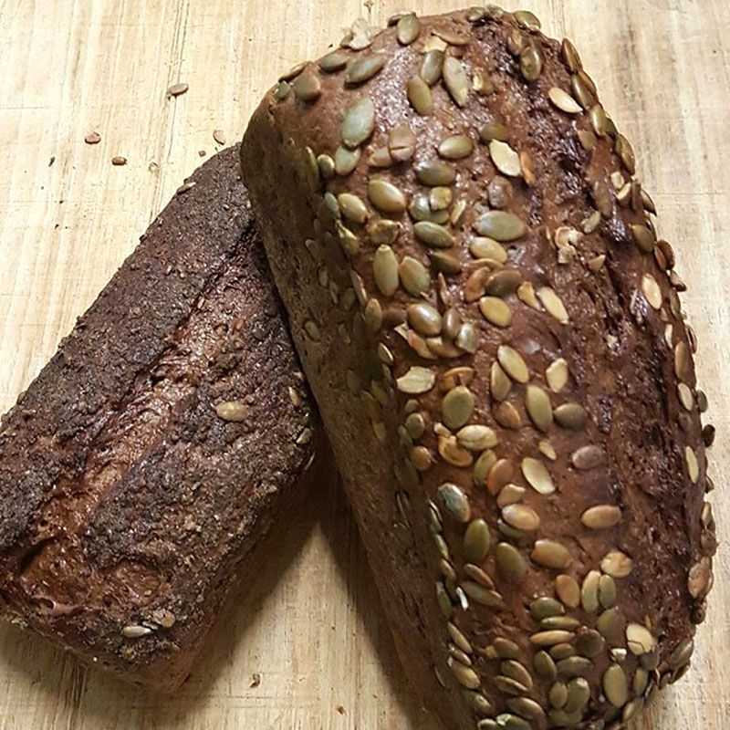 Zwei Laibe dunkles Schwarzbrot, einer mit Kürbiskernen.
