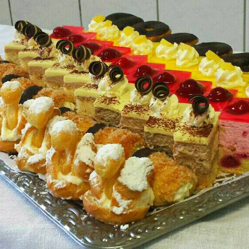 Tablett mit verschiedenen Gebäckstücken: Windbeutel, Kuchenquadrate und Donuts.