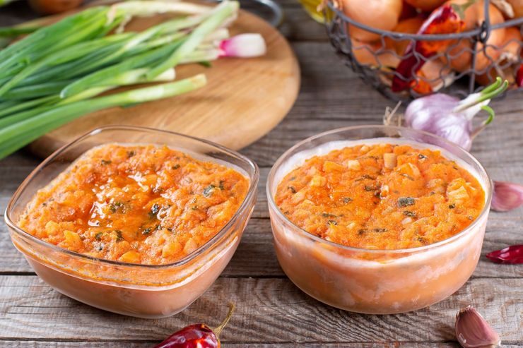 Deux bols de sauce épaisse sur une table rustique, avec des herbes et des légumes en arrière-plan.