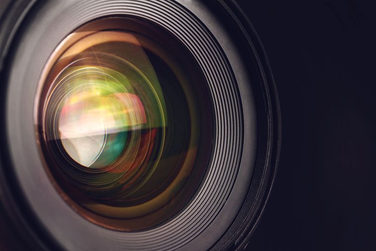Gros plan sur un objectif d'appareil photo avec des reflets irisés et des bords texturés.