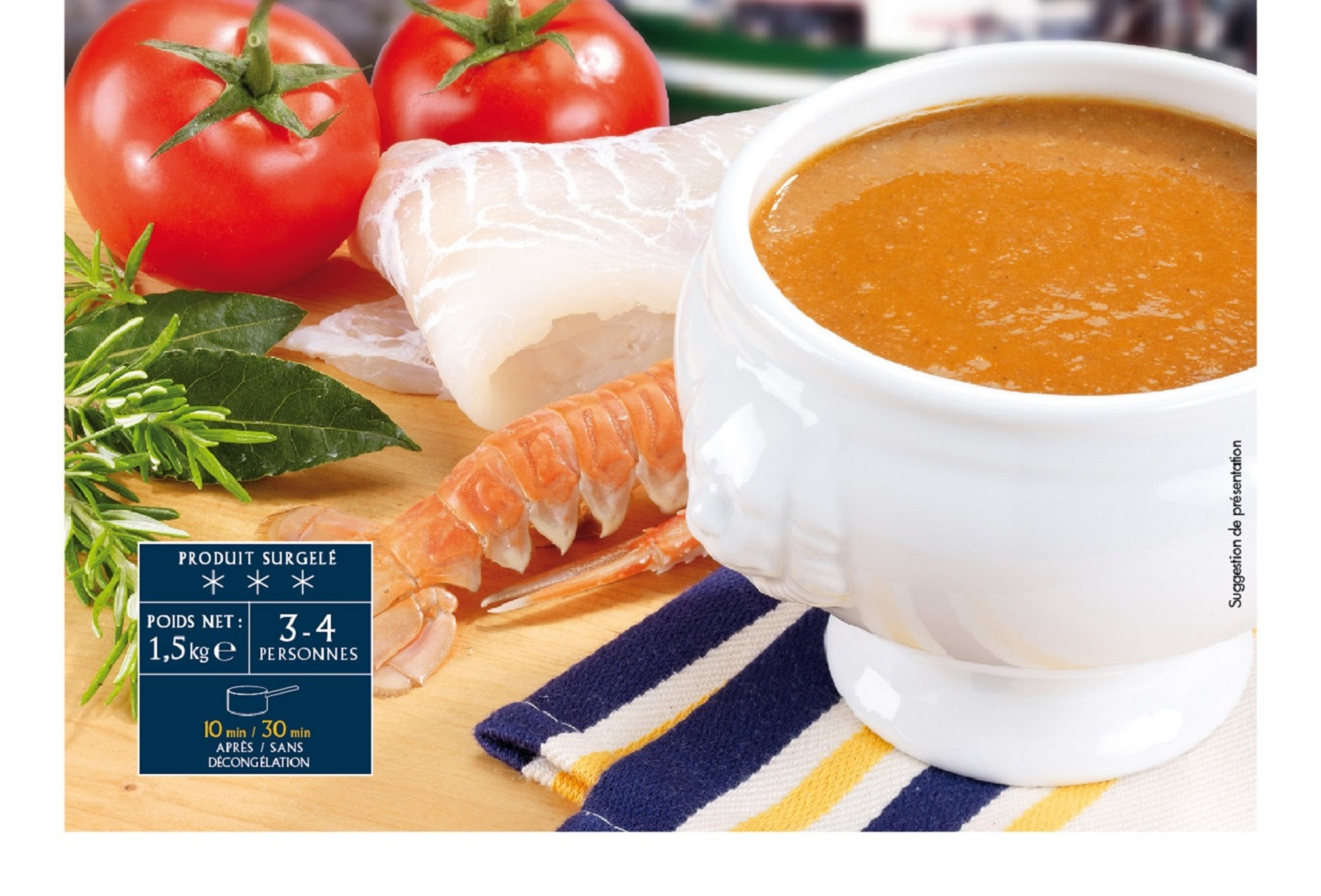 Bol de soupe à l'orange avec tomates, filet de poisson, crevettes et persil sur une nappe à rayures.