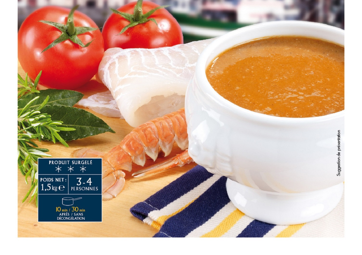 Soupe de tomates dans une tasse avec tomates, filet de poisson et légumes verts sur un linge rayé.