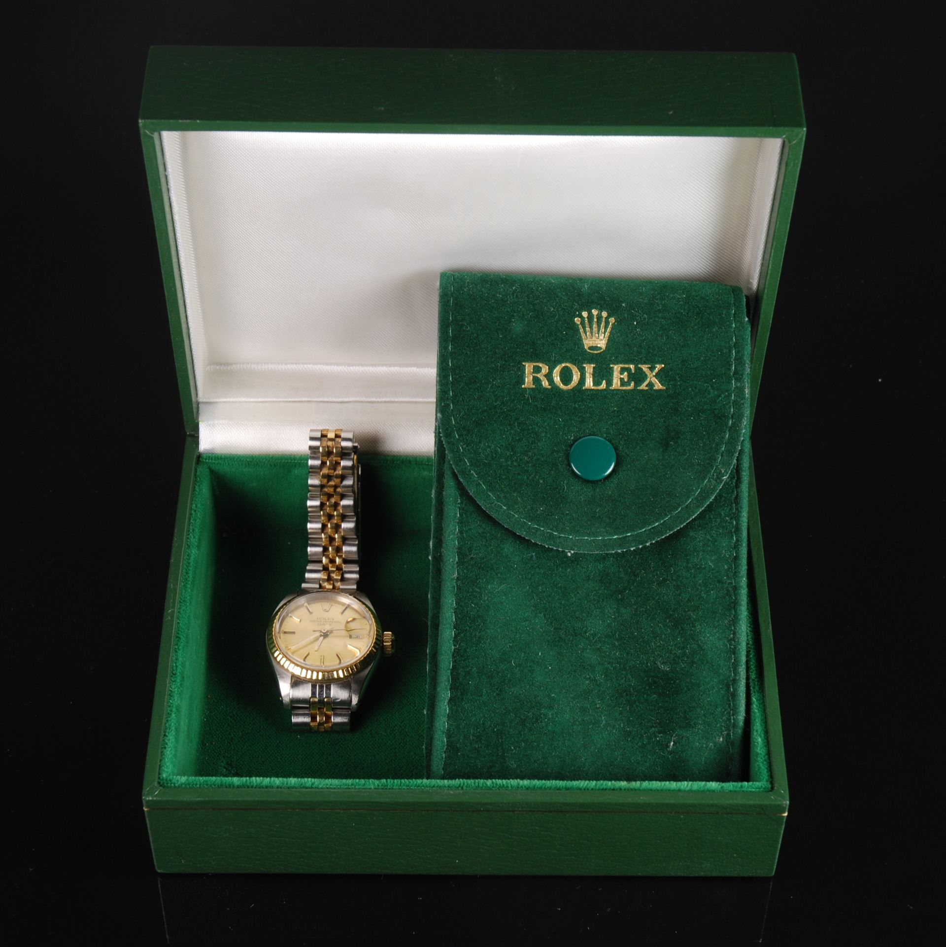 Montre Rolex en or et pochette Rolex verte dans un coffret de présentation vert.