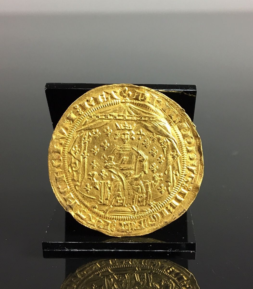 Pièce de monnaie en or sur un support noir, sur fond sombre.