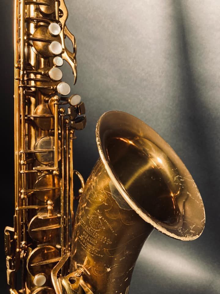Gros plan d'un saxophone doré sur fond gris.