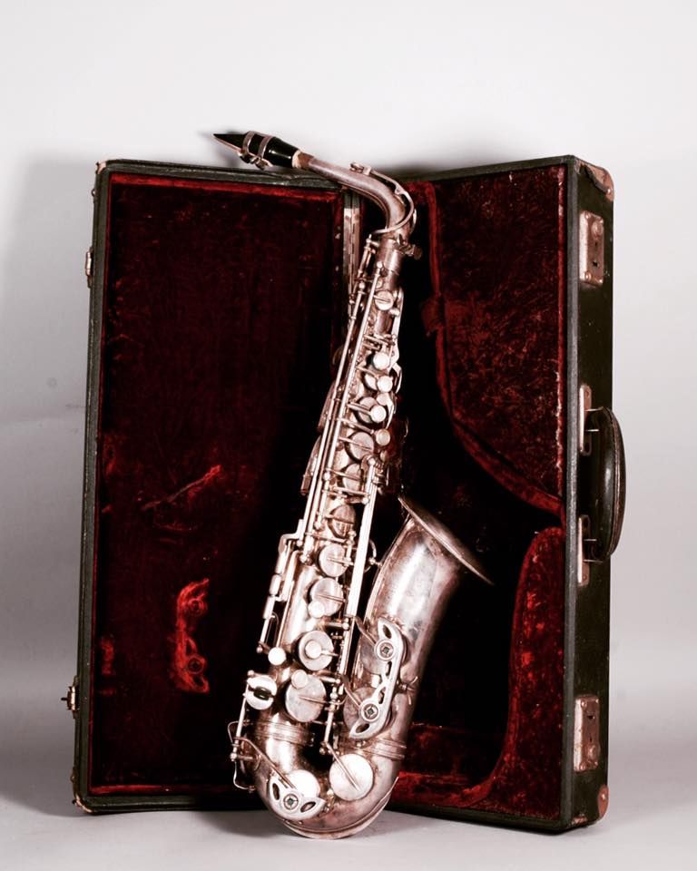 Saxophone argenté dans un étui ouvert en velours rouge foncé.