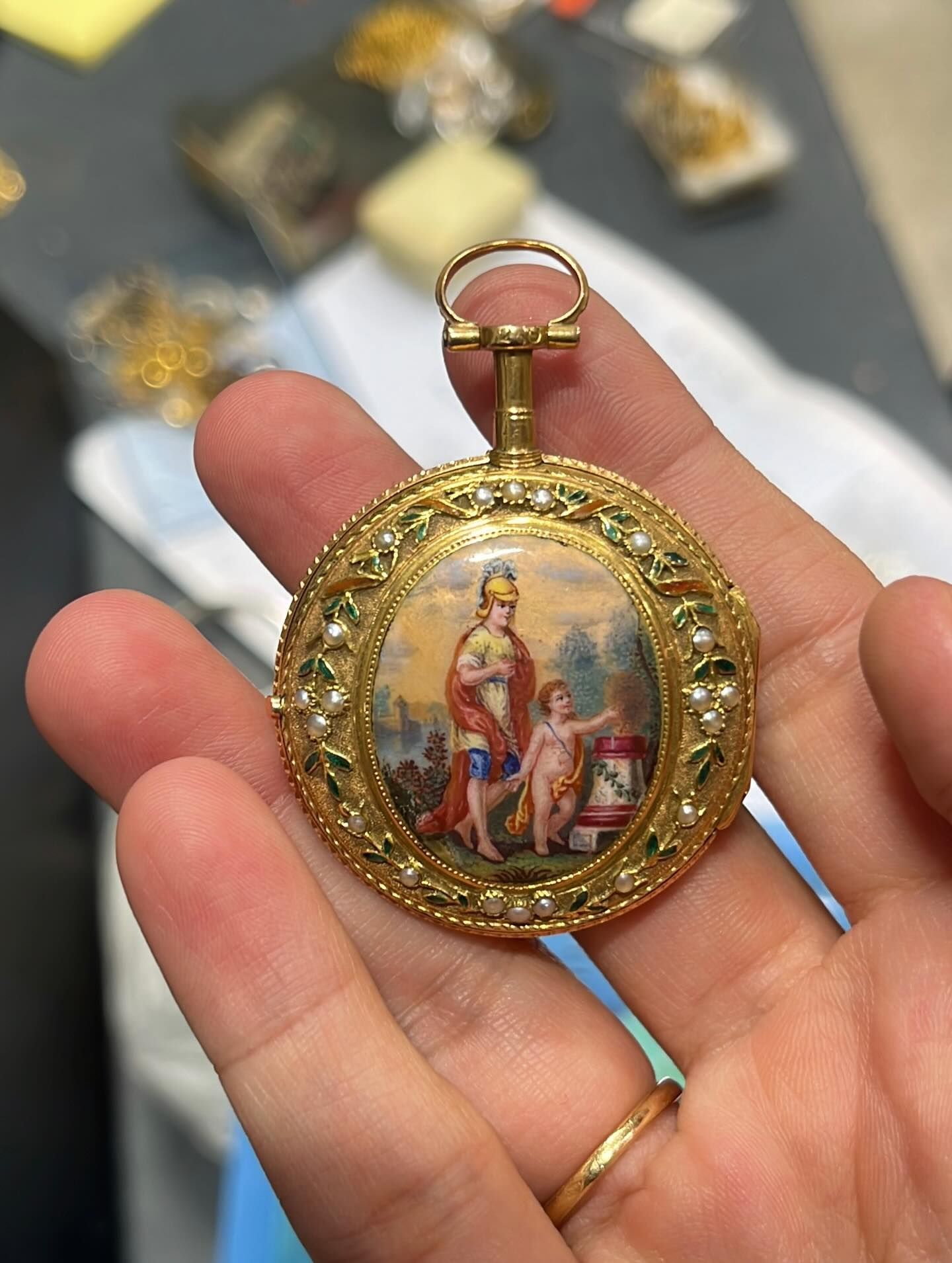 Une main tenant une montre à gousset en or ornée d'une image de saint.