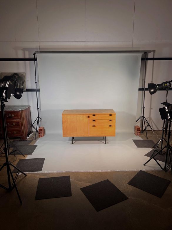 Aménagement d'un studio photo avec un fond blanc, une armoire orange au centre et des éclairages sur pieds tout autour.