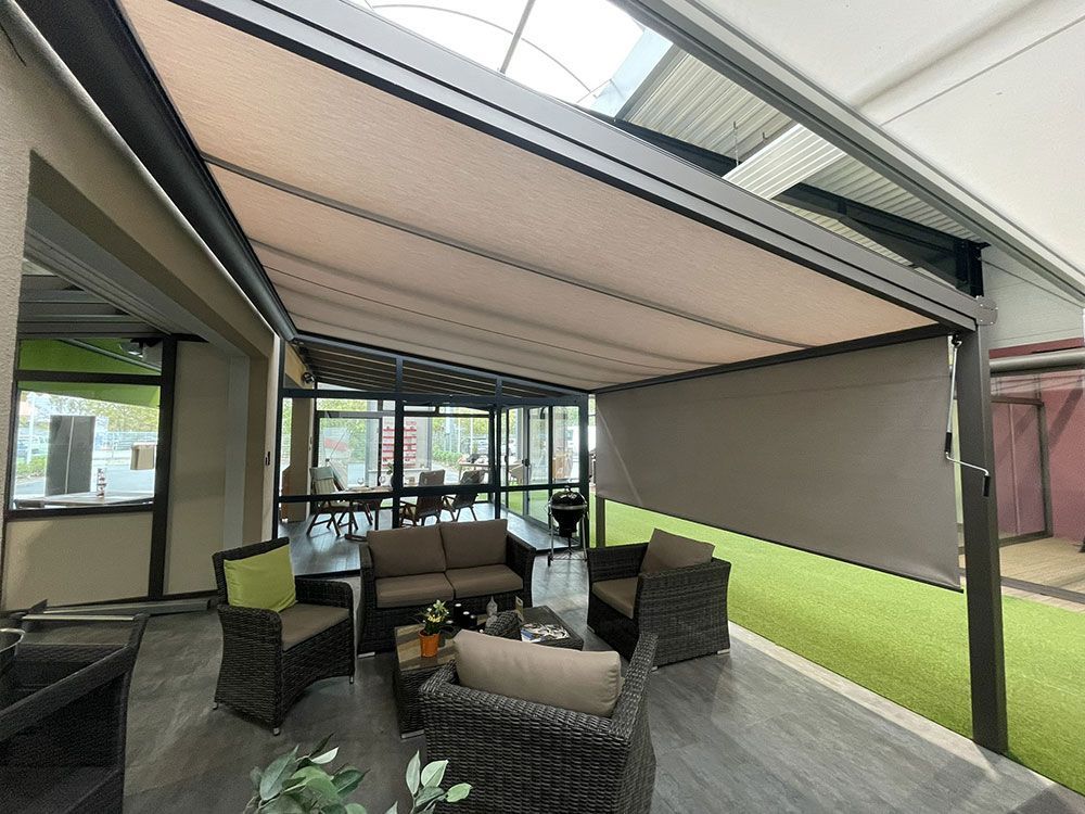Terrasse mit ausfahrbarer, hellbrauner Markise, Gartenmöbeln und Kunstrasenboden.