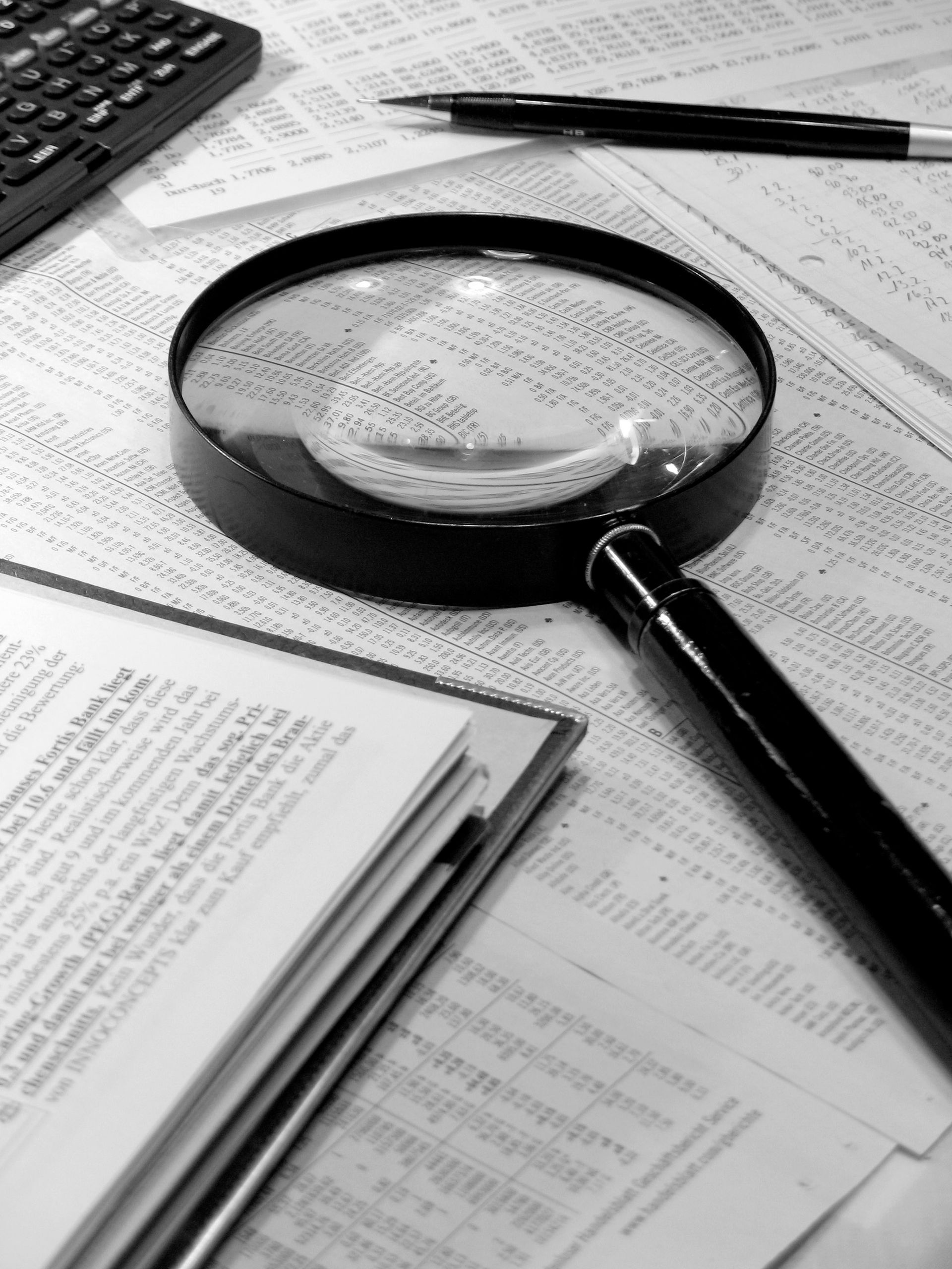 Eine Lupe liegt auf einem Stapel Papiere