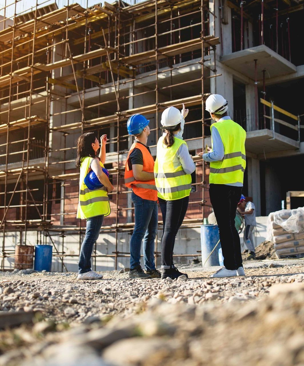 Eine Gruppe Bauarbeiter steht vor einem im Bau befindlichen Gebäude.