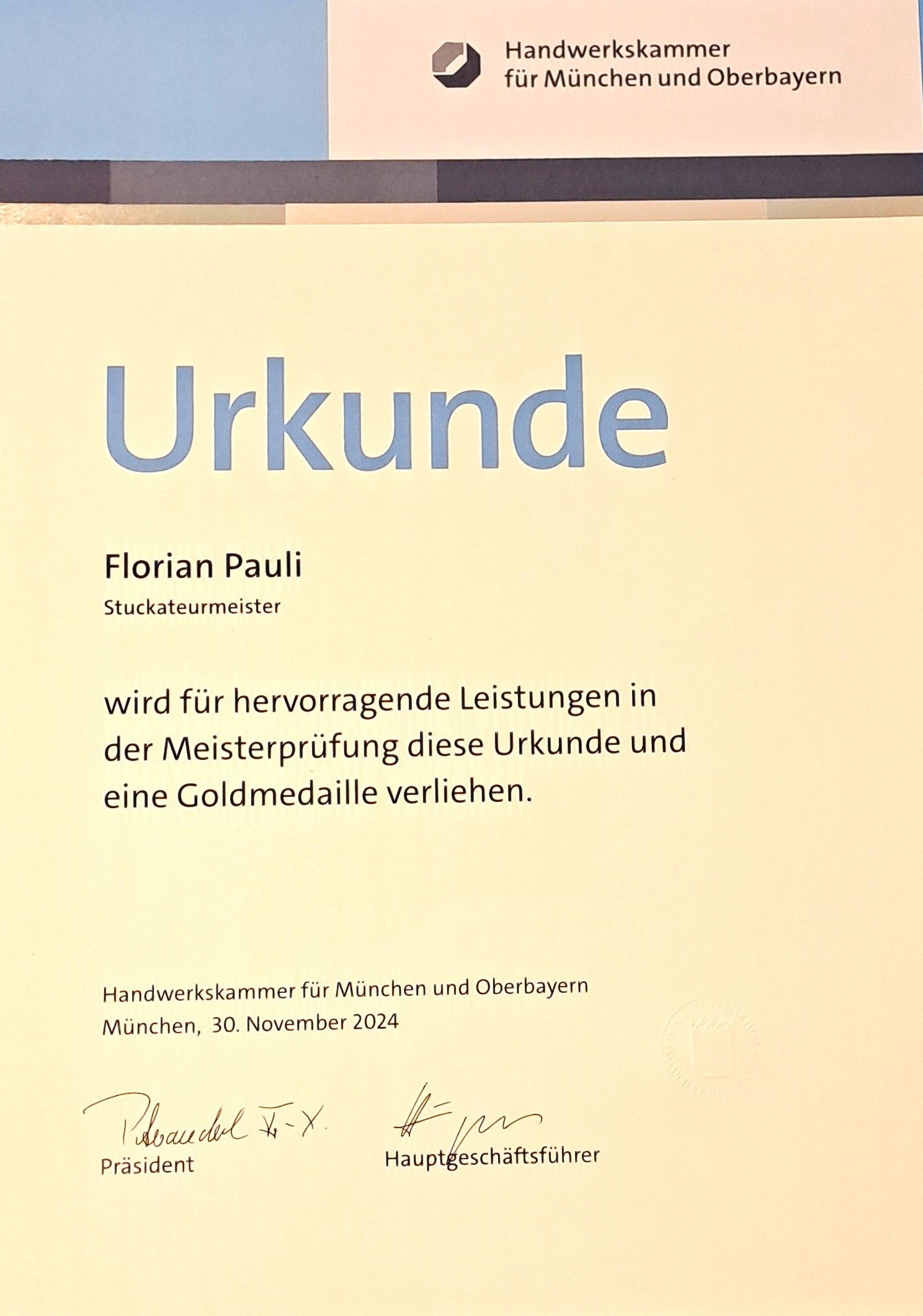 Urkunde mit Text zur Auszeichnung und Goldmedaille.