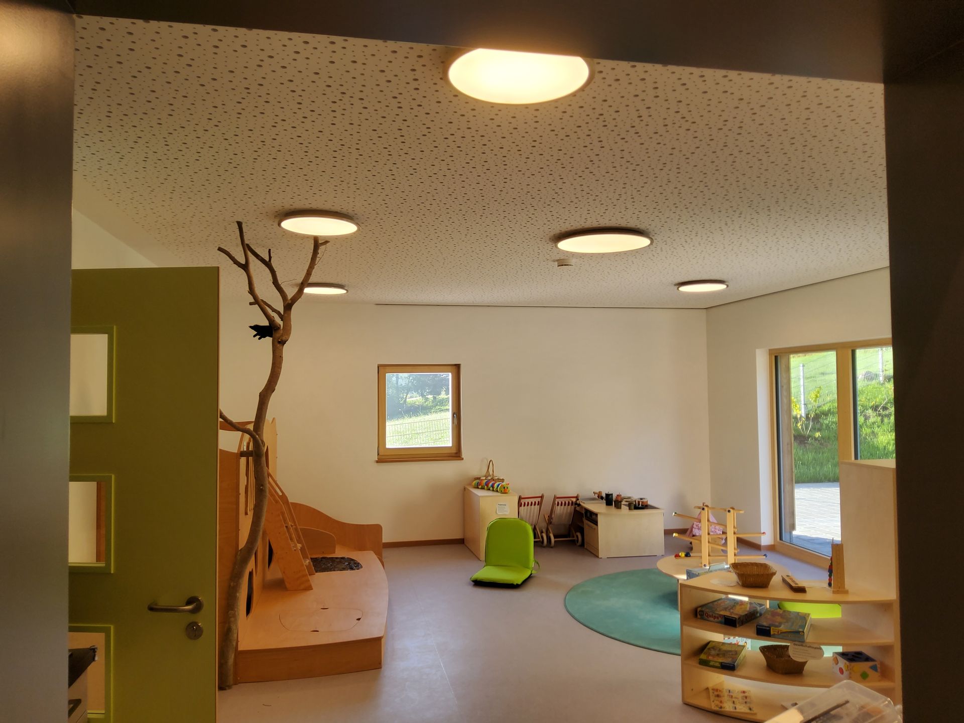 Heller Gruppenraum mit Spielmöbeln und Holzpodest im Kindergarten Freyung