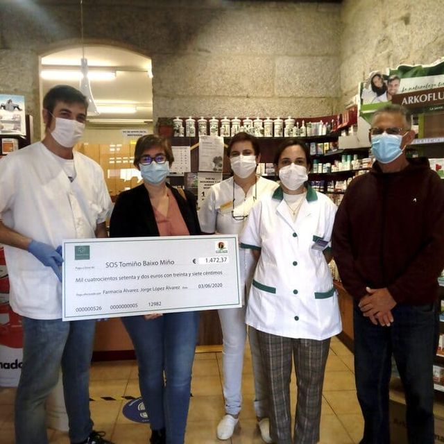 Un grupo de personas con mascarillas sosteniendo un cheque grande.
