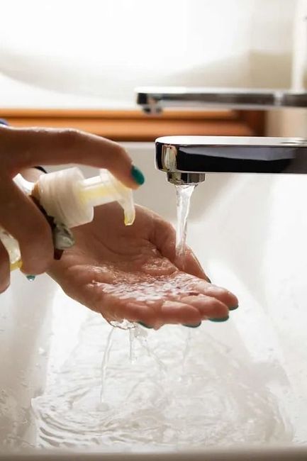 Una persona se lava las manos en un lavabo con jabón.