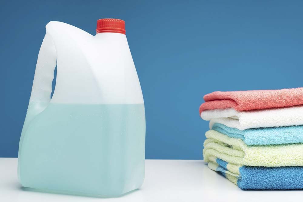 Jarra de detergente para ropa y pila de toallas dobladas de colores.