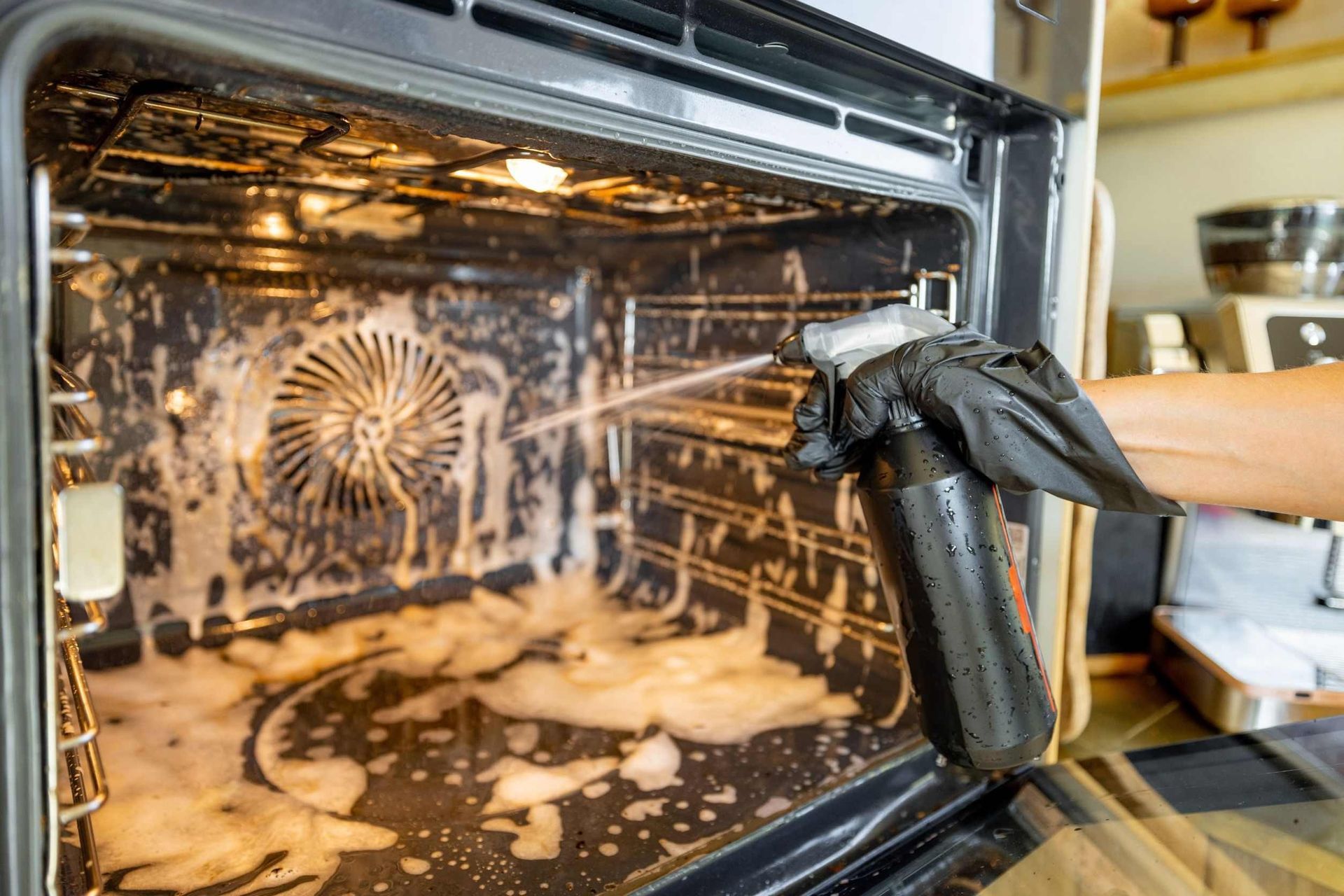 Una persona está limpiando un horno con una botella de spray.