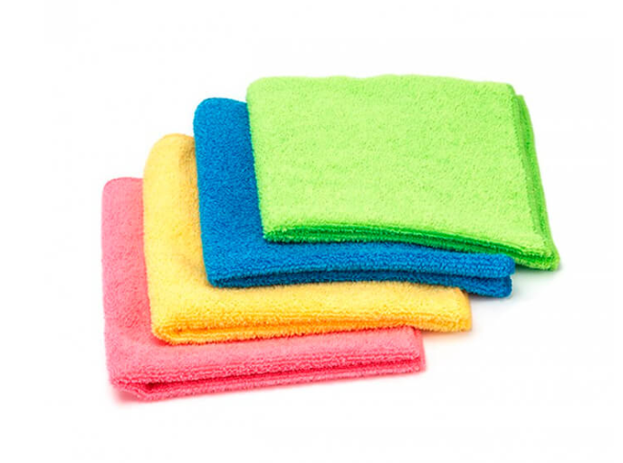 Cuatro toallas de colores se apilan una encima de otra sobre un fondo blanco.