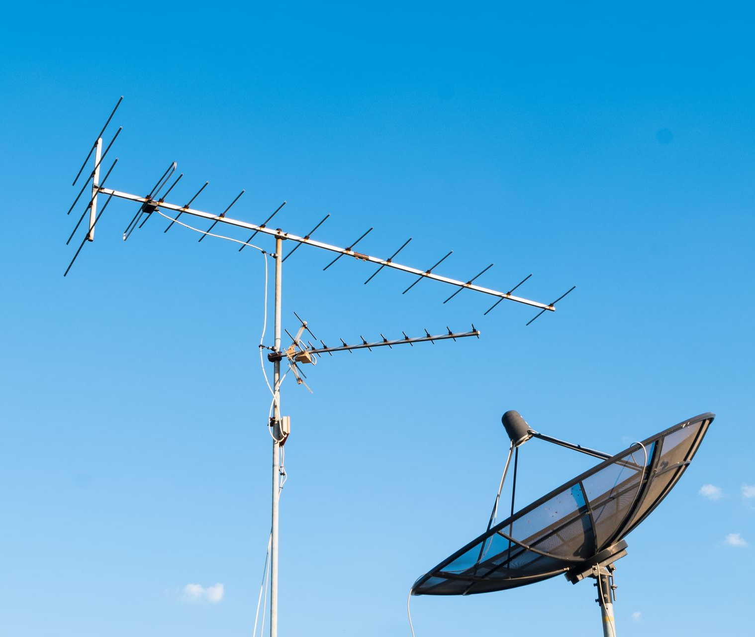 Antennes de télévision et parabole satellite sur fond de ciel bleu.
