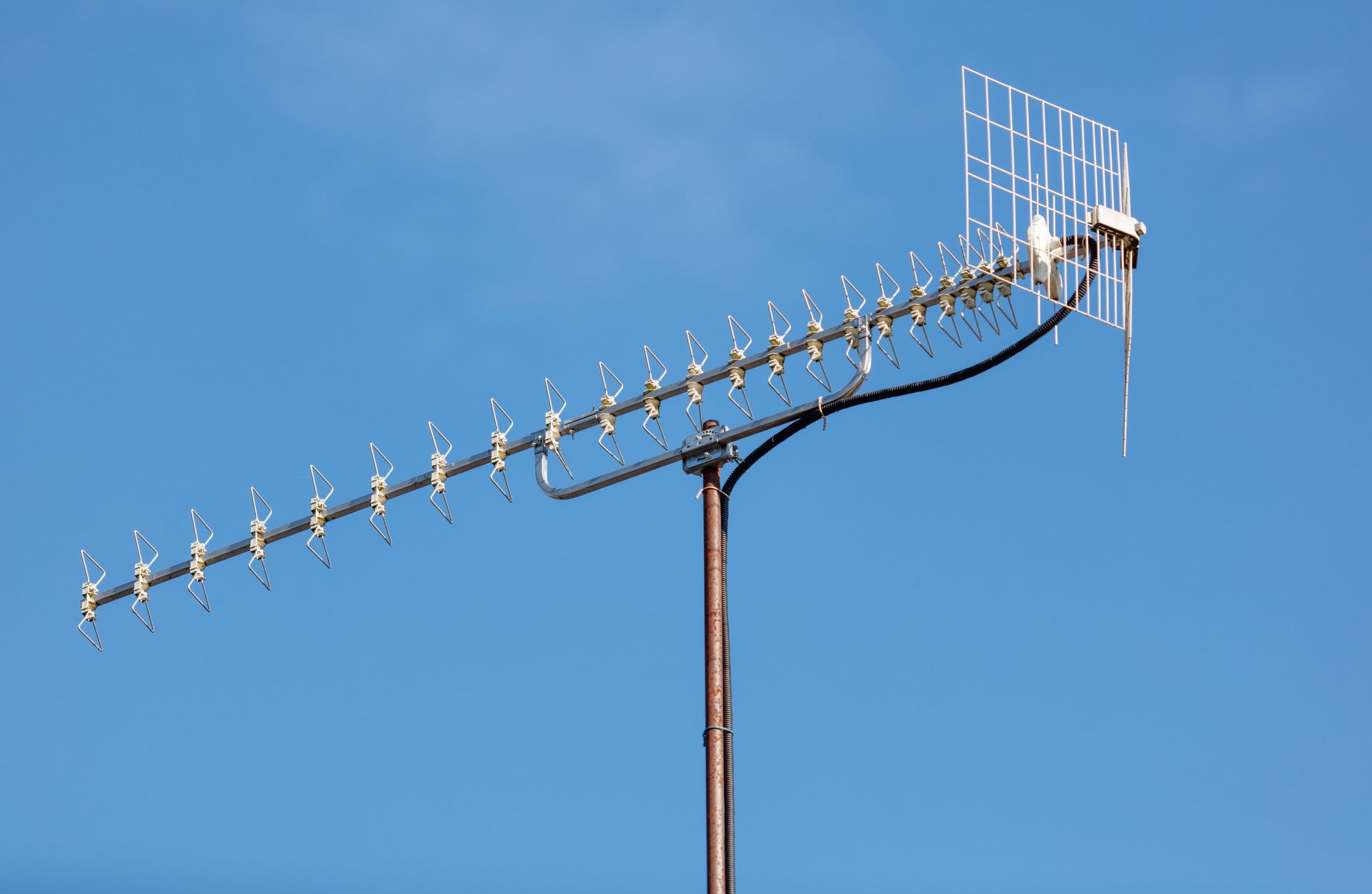 Une antenne de télévision argentée et blanche, fixée sur un mât.