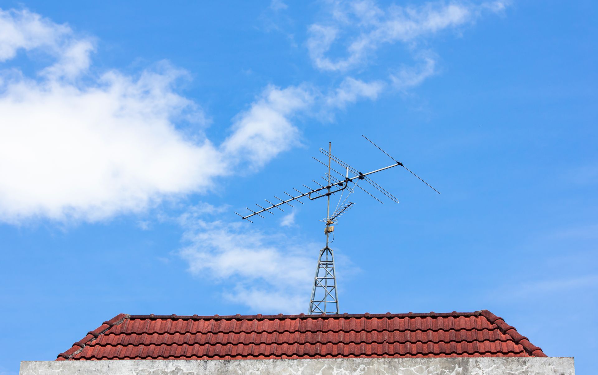 Antenne de télévision sur un toit de tuiles rouges.