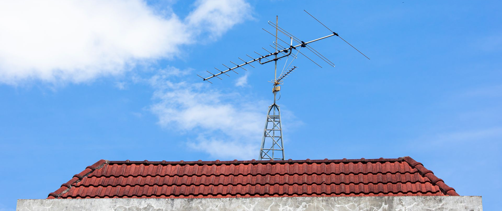 Antenne TNT sur un toit de tuiles rouges.