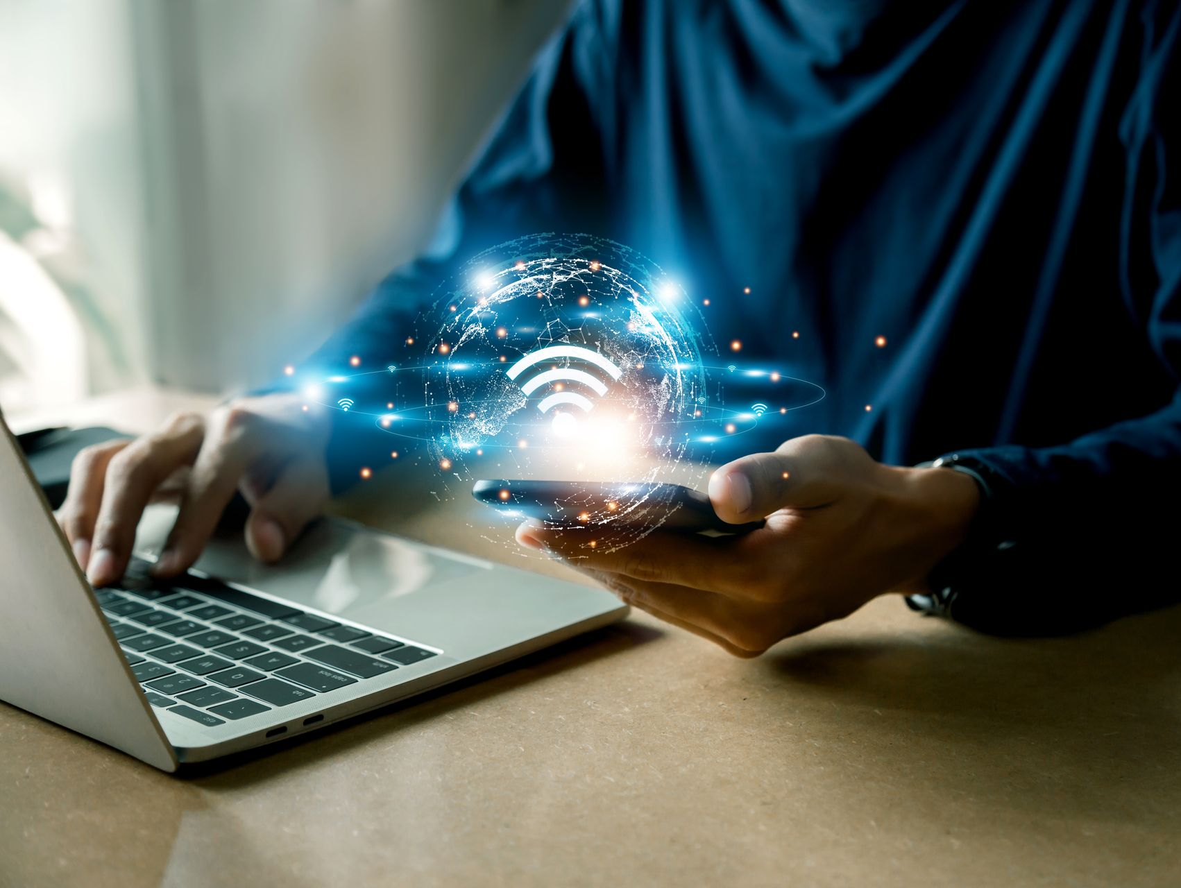 Une personne utilise un ordinateur portable et un smartphone avec un signal Wi-Fi lumineux superposé.