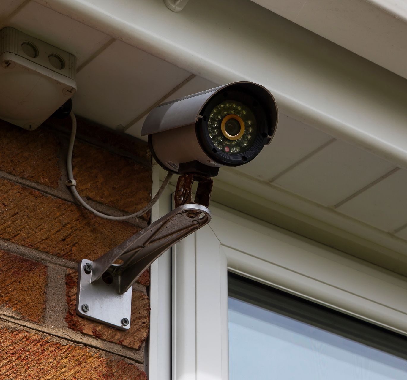 Une caméra de sécurité fixée sur un mur extérieur en briques.