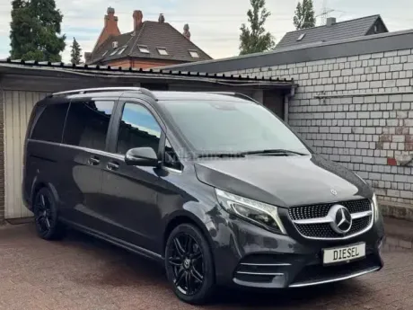 Furgoneta Mercedes negra aparcada junto a un garaje en la entrada de una vivienda.