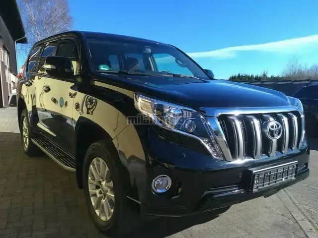 SUV negro estacionado en una entrada de vehículos, vista frontal izquierda, con parrilla cromada y cielo azul soleado.