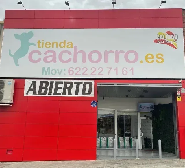 Entrada de una tienda de mascotas con señalización roja y blanca, una ilustración de un perro y la palabra