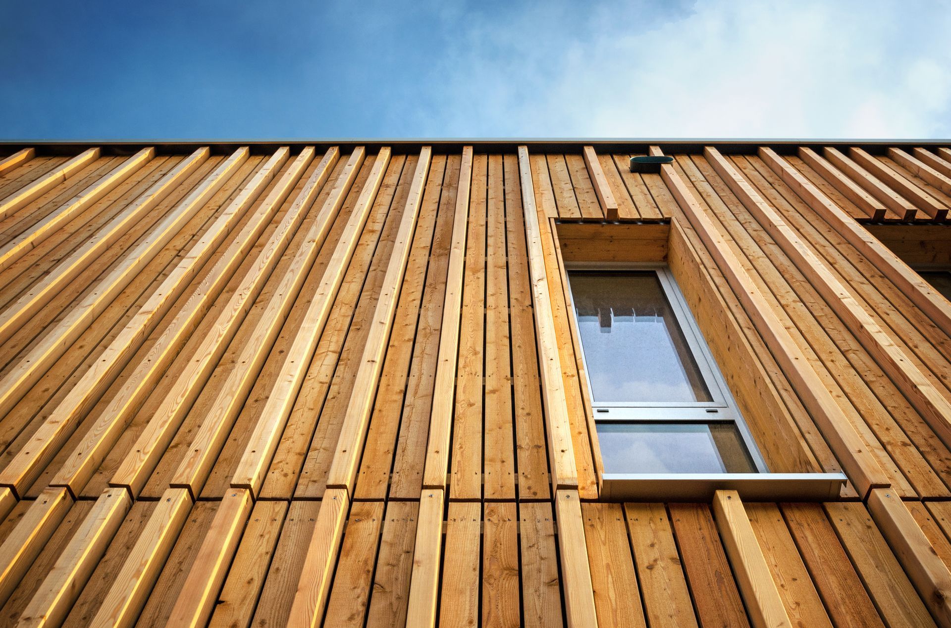 Extérieur d'un bâtiment en bois avec une fenêtre, contre un ciel bleu.