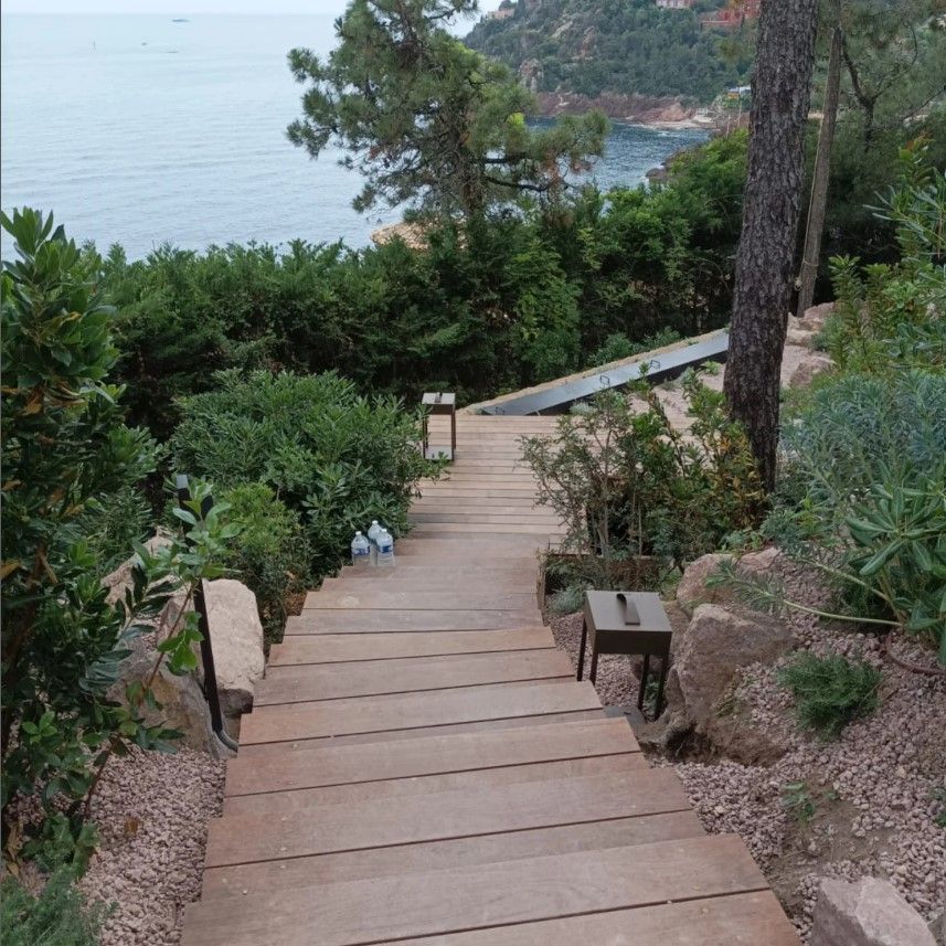 Escalier en bois menant d'un jardin à flanc de colline à la mer.